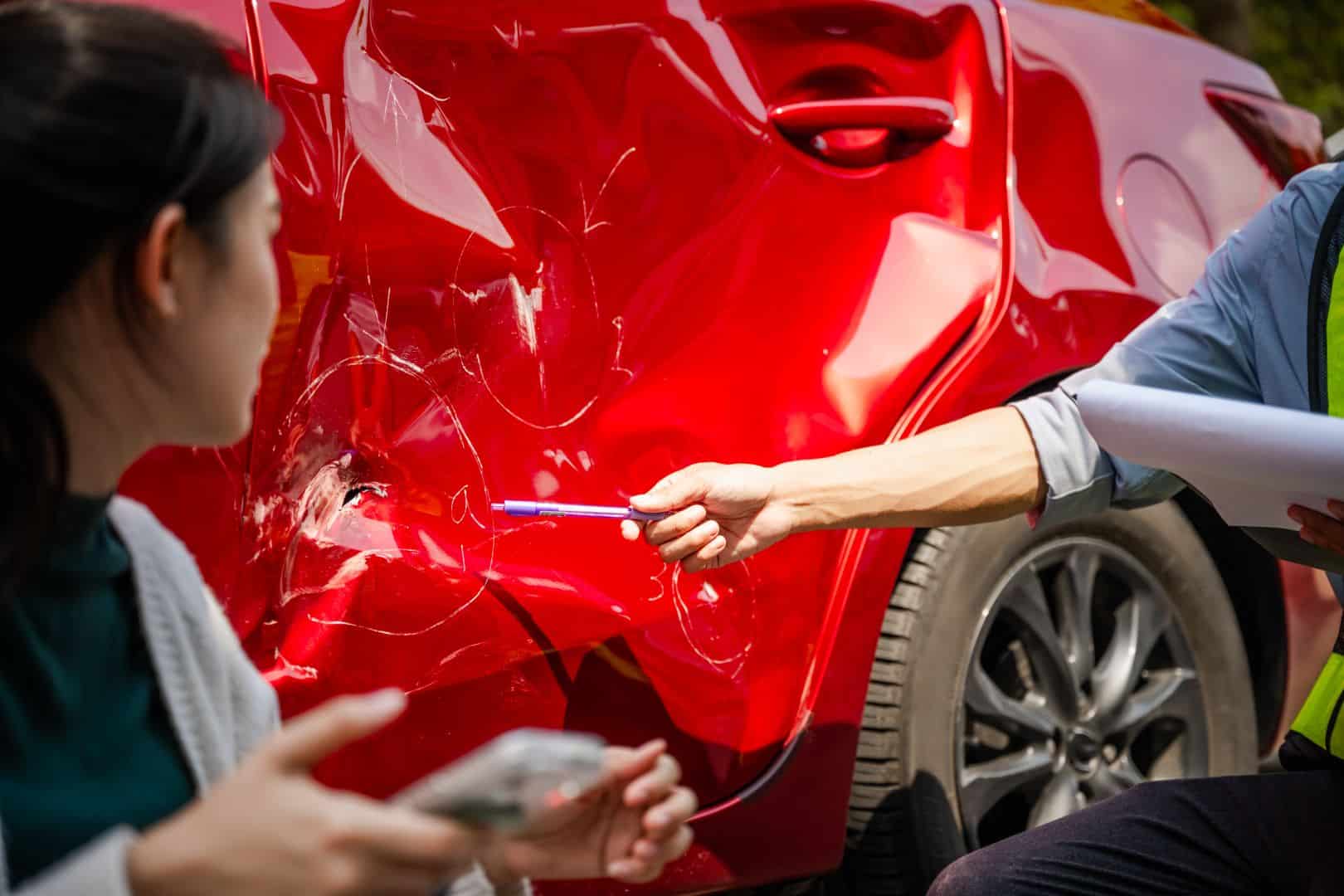 Car accident crash, Cars insurance protection, Claim collision, Auto emergency. A man is handing a woman a pen and a piece of paper. The woman is looking at the car that has been in an accident