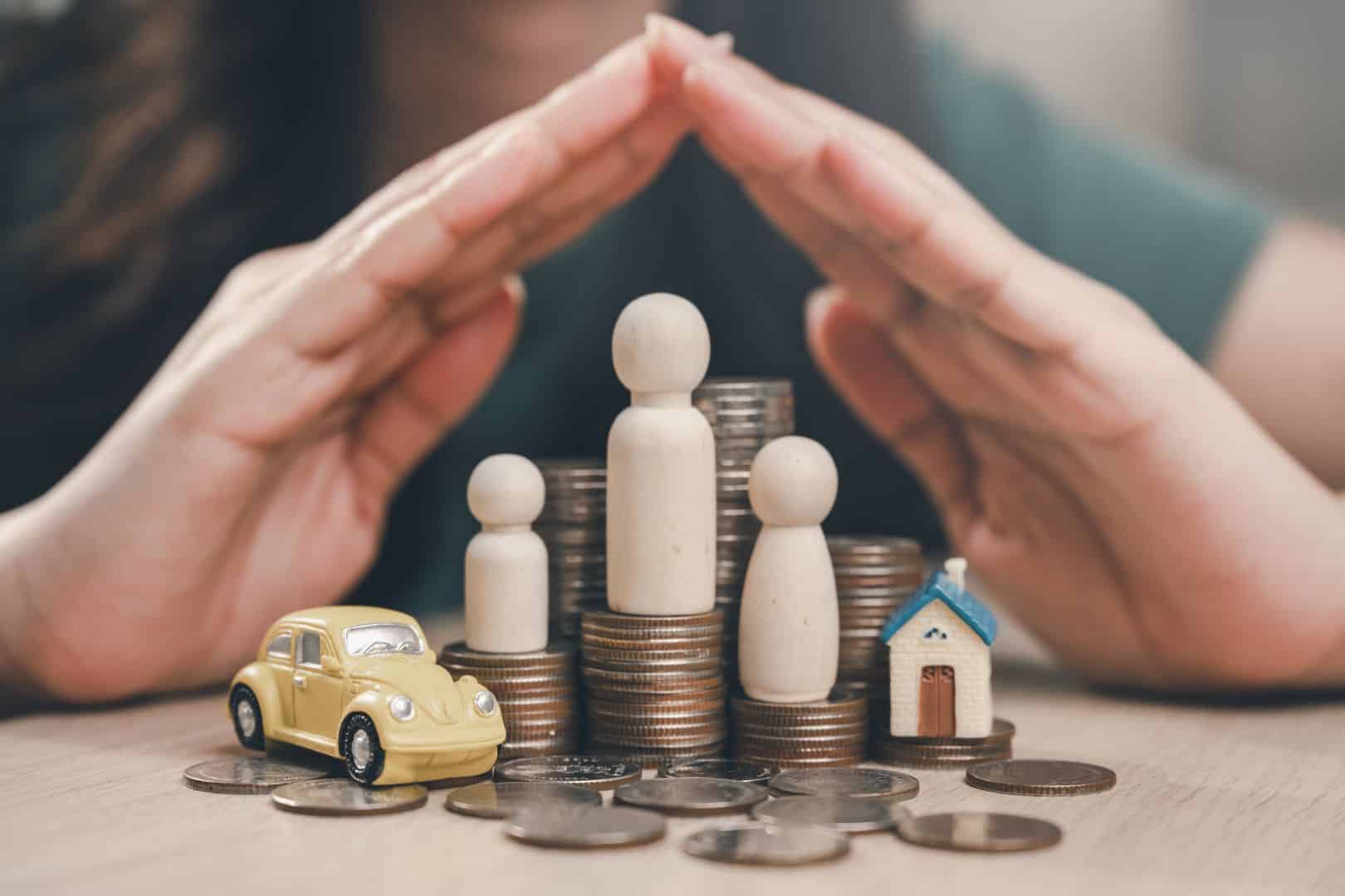 Family financial plan. Finance investment on real estate. Family invest in insurance save plan. A woman is holding her hand over a pile of coins and a toy car