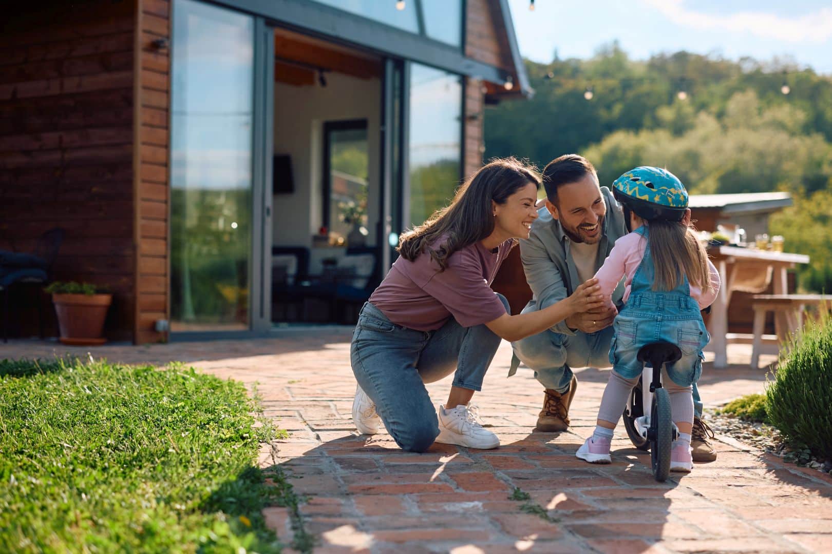 Happy parents having fun while teaching their daughter to ride bicycle